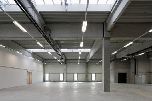 Flexible Produktions- und Logistikhalle mit stützenarmer Konstruktion, Tageslichtbändern und effizienter Industriearchitektur im Airline-Catering- und Logistikzentrum der SCK BBI Immobilien GmbH & Co. KG in Berlin-Schönefeld. Bauherr: SCK BBI Immobilien GmbH & Co. KG. Ort: Berlin-Schönefeld. Geplant und umgesetzt von arc+ GmbH Freudenstadt.